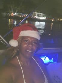 A festive moment captured on a boat at night, featuring a woman wearing a Santa hat, perfect for holiday celebrations on the water.