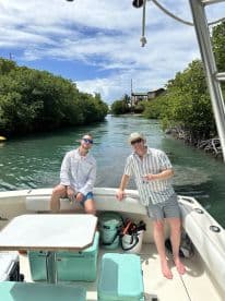 Two friends enjoy a sunny day on the boat, surrounded by lush mangroves and equipped with snorkeling gear — perfect for a fun day of exploration and adventure.