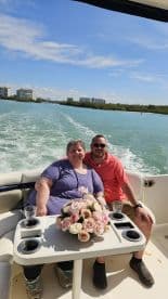 A happy couple enjoys a scenic boat ride, surrounded by beautiful flowers and sparkling waters — perfect for romantic outings or special celebrations.