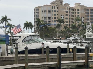 A sleek yacht named 'Sundancer' docked at a marina, surrounded by palm trees and residential buildings, showcasing a perfect boating getaway.