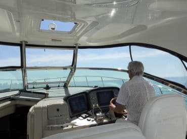 A captain navigates from the helm of a luxurious yacht, showcasing the modern console and spacious cabin design — perfect for comfortable cruising.