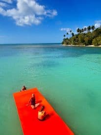 A fun day at the beach with friends enjoying a floating mat in crystal-clear waters — perfect for relaxation and summer adventures.