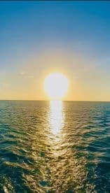 A breathtaking sunset over the ocean, reflecting golden hues on the water — a perfect backdrop for memorable boating experiences.