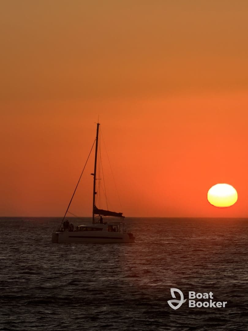 A serene sunset view featuring a catamaran sailing on calm waters, creating a picturesque backdrop for evening cruises.