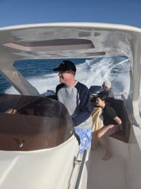 A family enjoys a day on the water, with one adult at the helm and children relaxing on board — perfect for creating lasting memories on a boating adventure.