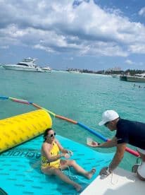 A woman enjoys a refreshing cocktail while relaxing on a floating mat in the turquoise waters, showcasing the perfect blend of leisure and fun on a sunny day.