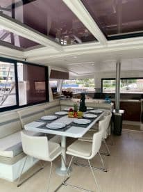 A beautifully arranged dining area inside a boat, featuring a table set for a meal with plates and a centerpiece of fresh fruit, perfect for onboard dining experiences.