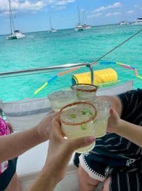 A group toasts with refreshing cocktails aboard a boat, enjoying a vibrant day on the water — perfect for celebrations and fun outings.