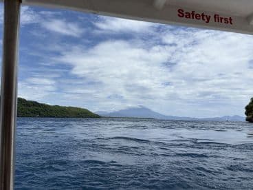 A scenic view of a lush coastline and distant mountains from a boat, showcasing the beauty of the surrounding landscape — perfect for nature lovers and adventure seekers.