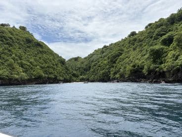 A stunning view of lush green hills surrounding a tranquil bay, perfect for exploring hidden gems and enjoying nature's beauty on a boating adventure.