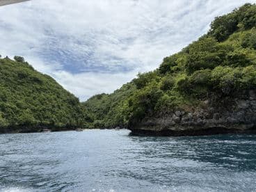 A stunning view of lush green hills framing a tranquil bay, perfect for exploring hidden coves and enjoying nature's beauty on a boating adventure.