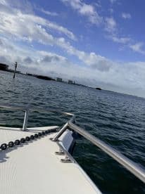 A close-up view of the bow of a boat cruising through calm waters, showcasing the sleek design and tranquil surroundings — perfect for a day on the water.