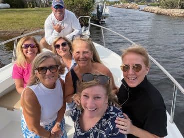 A cheerful group of friends poses for a selfie on a boat, capturing the joy of their day on the water together.