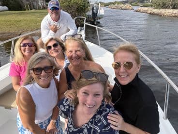 A joyful group of friends poses for a selfie on a boat, capturing the essence of a fun day on the water together.