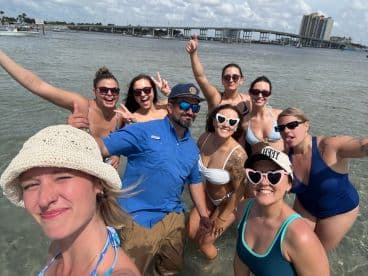 A lively group of friends enjoys a fun day at the beach, posing for a selfie while swimming in the water — perfect for memorable summer outings.