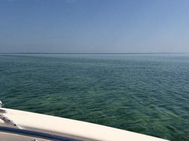 A serene view from the bow of a boat, showcasing the clear turquoise waters and a tranquil horizon — perfect for a day of relaxation on the water.
