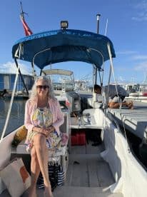 A woman relaxes in the cabin of a boat, showcasing a cozy interior space with vibrant decor — perfect for enjoying a day on the water.