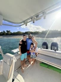 A joyful family poses together on a boat, capturing a memorable moment against a beautiful tropical backdrop — perfect for family outings and adventures on the water.