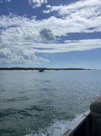 A scenic view of a boat cruising through calm waters, with a picturesque coastline and vibrant sky in the background — perfect for capturing the essence of a relaxing day on the water.
