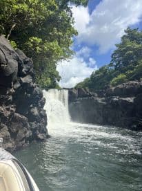 A stunning view of a waterfall surrounded by lush greenery, captured from a boat — a perfect representation of nature's beauty during a scenic water tour.