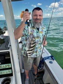 A man proudly displays his catch while fishing on a boat, showcasing the thrill of a successful fishing trip on the water.