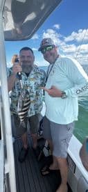Two anglers proudly display their catch while fishing on a boat, capturing the excitement of a successful day on the water.