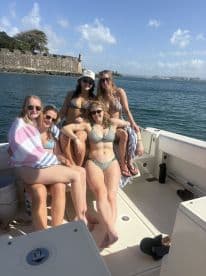 A lively group of friends enjoys a sunny day on the boat, showcasing their fun and carefree spirit while soaking up the sun.