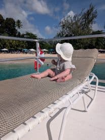 A cute baby relaxes on a lounge chair by the beach, enjoying the sun and the serene surroundings — a perfect family moment on a boating trip.