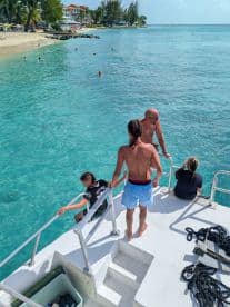 A family enjoys a sunny day on the boat, with some members preparing to jump into the crystal-clear waters — a perfect moment for summer fun and relaxation.