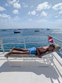 A young boy relaxes on a sunbed aboard a boat, enjoying the serene ocean views — a perfect moment for sunbathing and relaxation on the water.