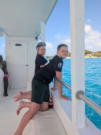Two kids enjoy the ocean view from the side of a boat, ready for a snorkeling adventure — a perfect moment of excitement on the water.