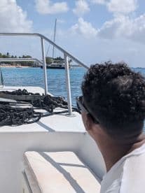 A guest enjoys the view from the deck of a boat, taking in the beautiful scenery and calm waters — perfect for a relaxing day on the water.