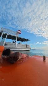 A person relaxes on an inflatable mat in the ocean while a boat is anchored nearby, capturing the essence of a perfect day on the water.