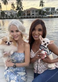 Two friends enjoy a picturesque sunset on a boat, each holding their adorable dogs — a perfect moment for pet lovers and sunset enthusiasts.