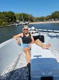 A woman relaxes on the deck of a boat under the sun, enjoying a perfect day on the water.
