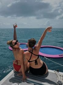 Two friends celebrate with cocktails on a boat, enjoying the sun and water — a perfect moment for fun and relaxation on the water.