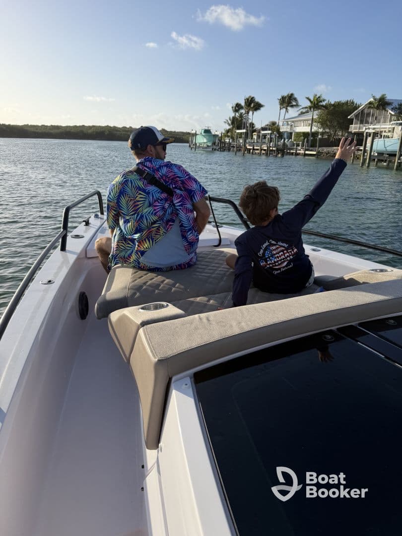 A joyful moment on the water as a child waves while enjoying a boat ride with an adult, capturing the essence of family fun and adventure.