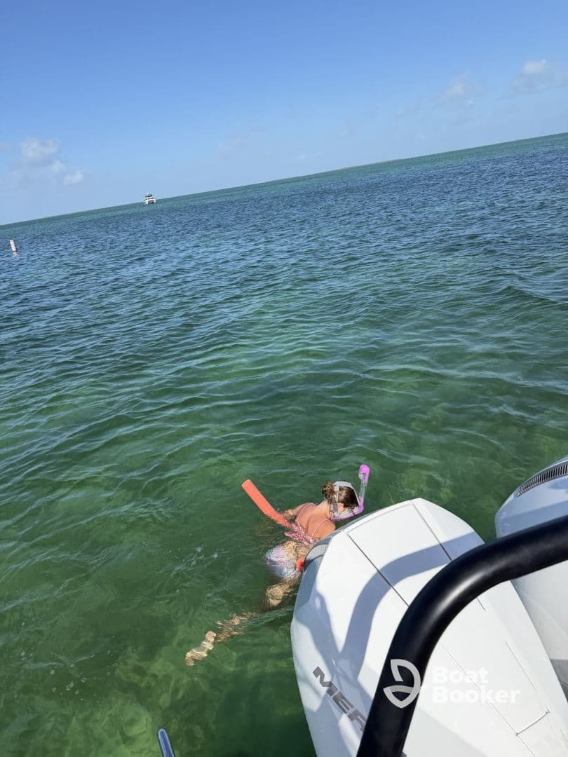 A person enjoys snorkeling in clear waters, showcasing the fun and adventure of aquatic activities while on a boating trip.
