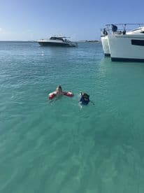 Two children enjoy a fun day of snorkeling and swimming in crystal-clear waters, with boats anchored nearby — a perfect family adventure on the water.