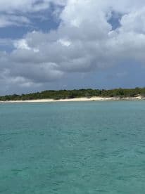A serene view of a secluded beach with lush greenery and clear turquoise waters, perfect for a relaxing getaway or island exploration.
