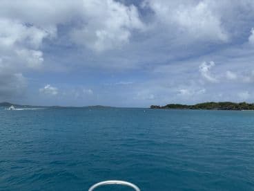 A scenic view of the open water with a boat in the distance, showcasing the beautiful turquoise sea and cloudy sky — perfect for boating enthusiasts and nature lovers.