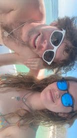 A joyful couple poses for a selfie at the beach, enjoying the sun and each other's company — perfect for capturing memorable moments during a tropical getaway.