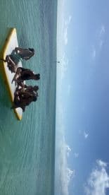 A lively group enjoys a sunny day on a paddleboard in clear waters, perfect for fun and relaxation under the sun.