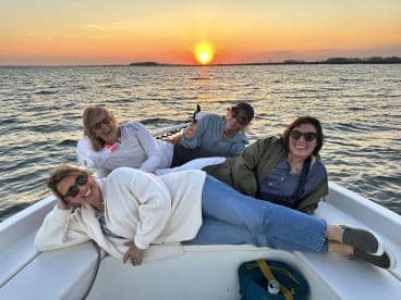 A group of friends enjoys a stunning sunset aboard a boat, capturing the perfect moment of relaxation and camaraderie on the water.