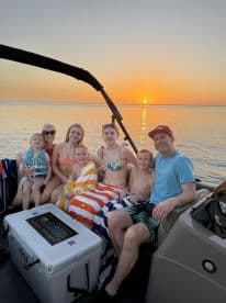 A joyful family poses for a photo on their boat at sunset, creating lasting memories during their boating adventure.