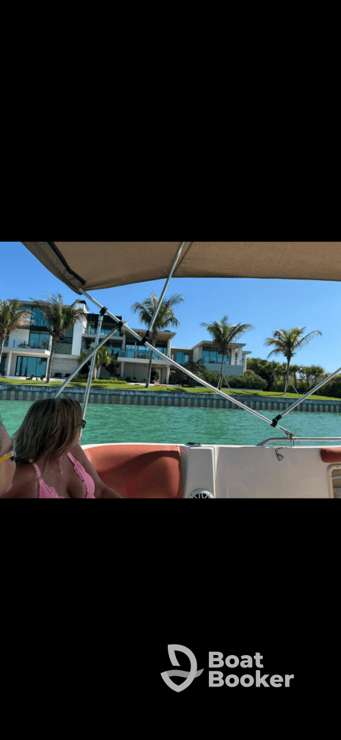 A guest enjoys a relaxing moment on a boat, with stunning waterfront properties and palm trees in the background — perfect for scenic boat tours.