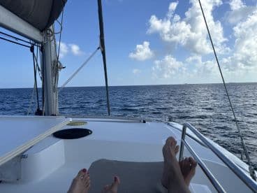 A relaxing view from the cabin of a sailboat, showcasing feet resting on the deck with a serene ocean backdrop — perfect for unwinding on a sailing adventure.