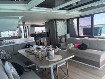 A stylish interior view of a catamaran's lounge area, featuring comfortable seating and a dining table, perfect for relaxing and enjoying the scenic views while on the water.