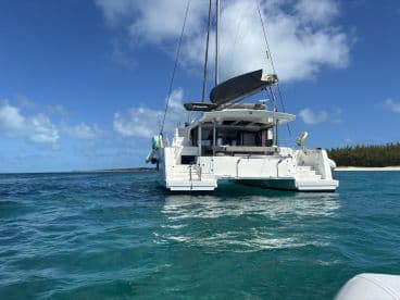 A stunning view of a catamaran cruising through crystal-clear waters, showcasing its sleek design against a backdrop of tropical scenery.
