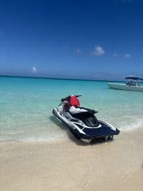 A Yamaha jet ski rests on the sandy beach, inviting adventure seekers to enjoy thrilling water sports in the crystal-clear waters.